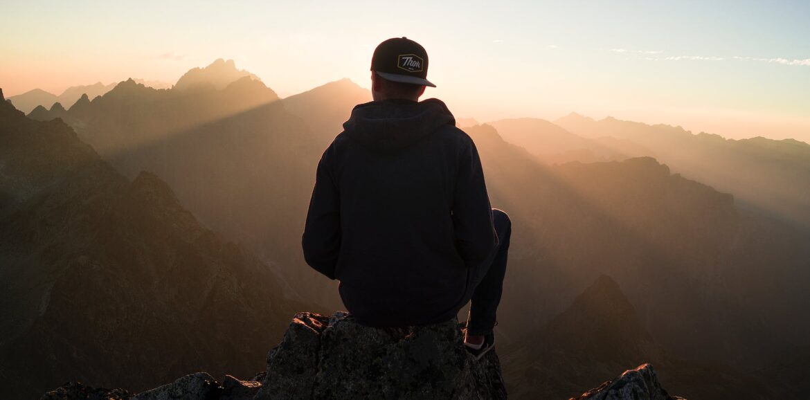 man sitting on the mountain edge